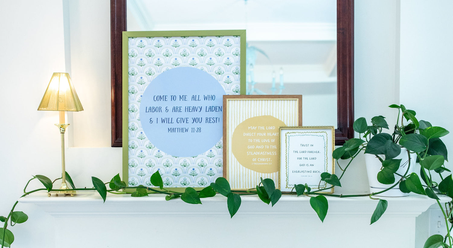 Decorative shelf with framed prints and a lamp, featuring motivational quotes.